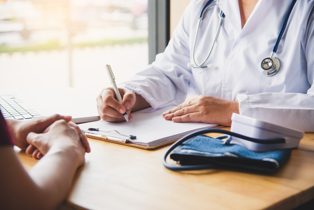 Cropped image of a doctor taking notes while speaking to a patient