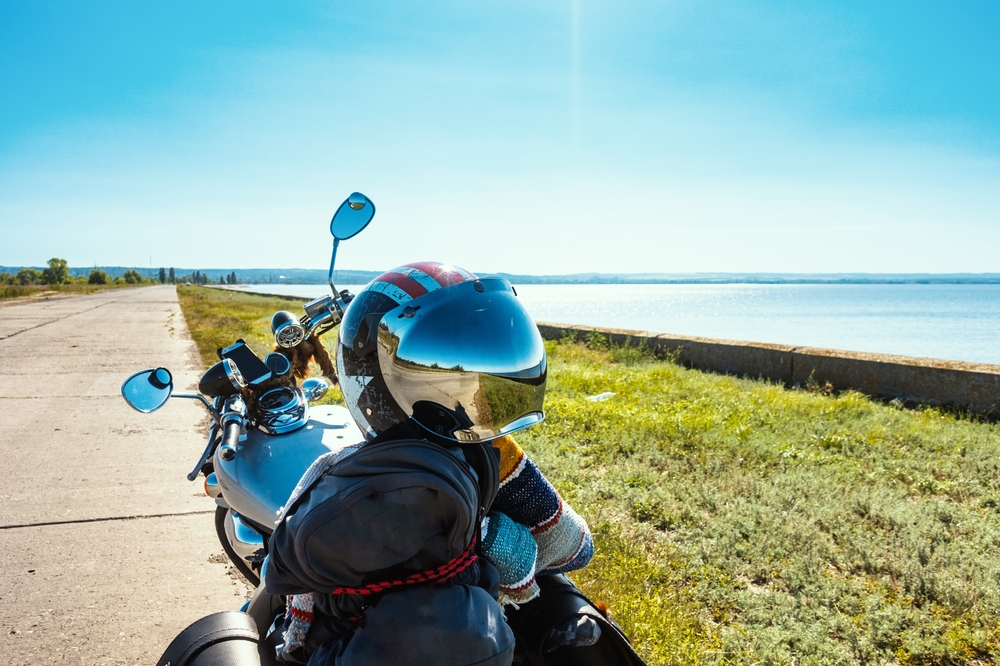 Parked motorcycle with helmet parked on a trail by a body of water